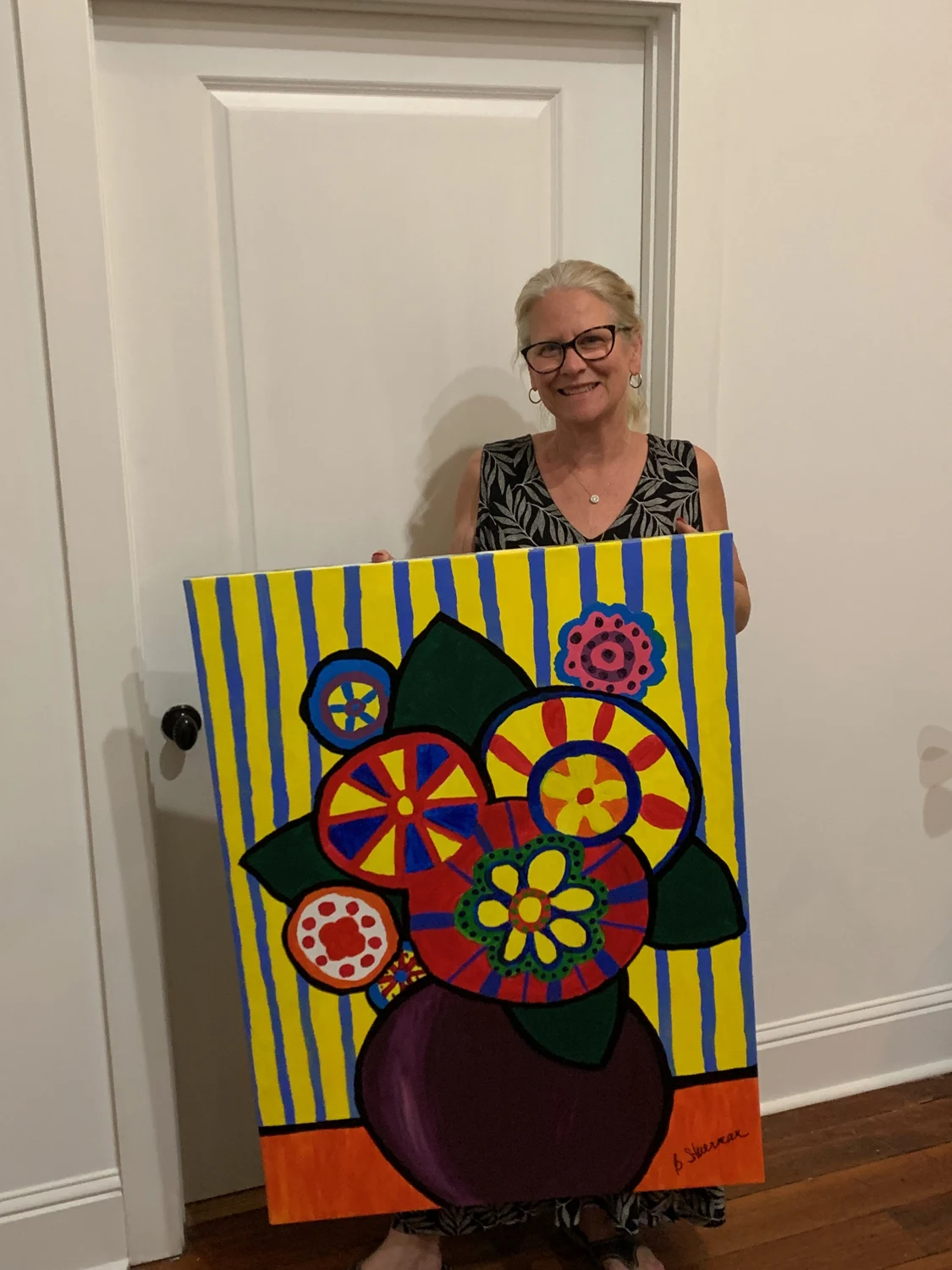 Beth Stuerman holding her colorful painting of flowers in a vase